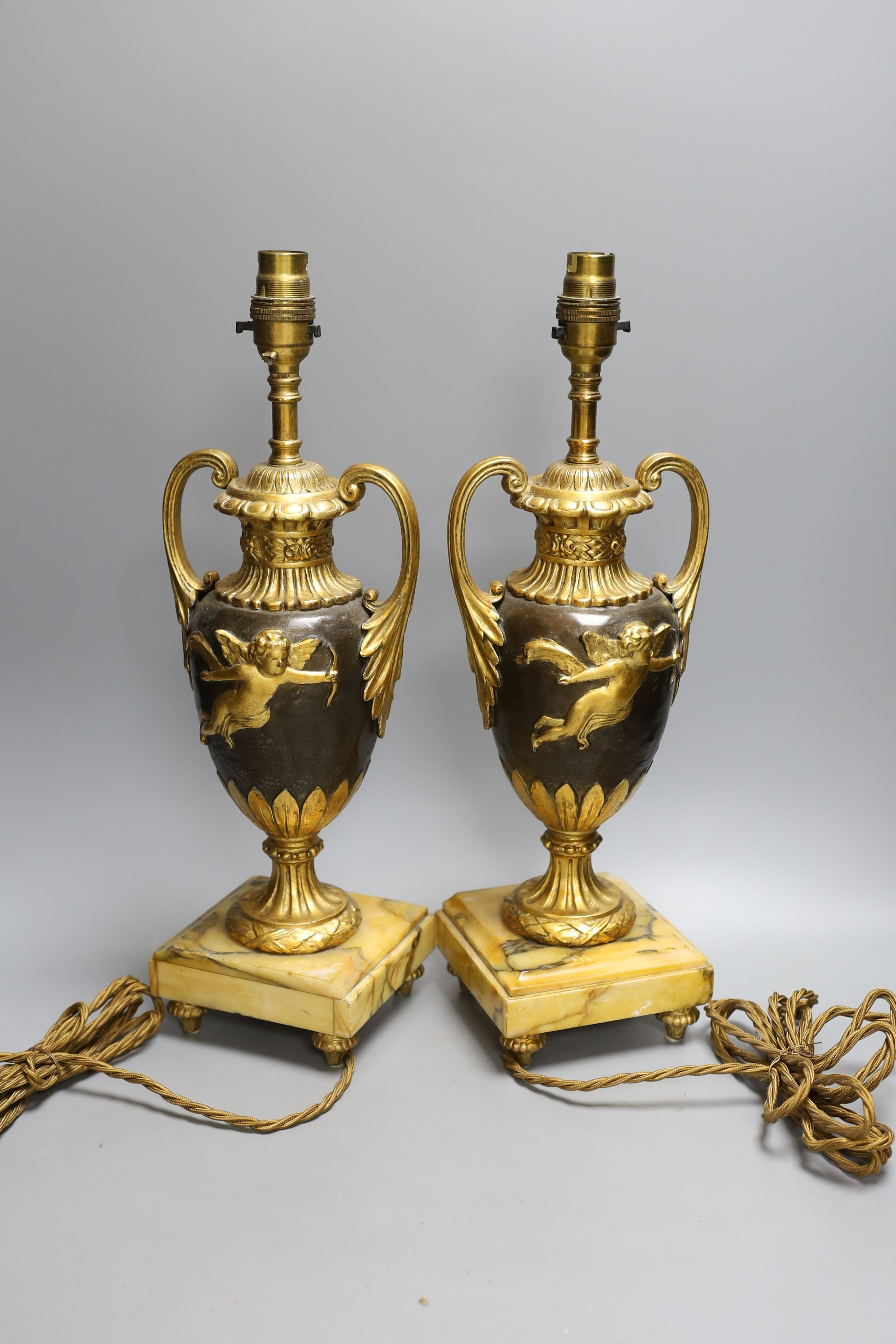 A pair of ornate guilt vase style lamps on marbled base, together with a seated cherub table lamp, 45cm tall, (3)